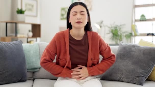 腹部,便秘や胃の痛みを持つ病気の女性,月経けいれんや食中毒.消化不良、痛みを伴うと下痢を持つアジアの女性、ソファの上での期間のクランプで膨満感と苦しみ. - 映像、動画