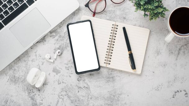 Weißer Schreibtischarbeitsplatz mit Smartphone, Laptop, Brille, Notizbuch, Stift und Kaffeetasse, Flachbildschirm mit Kopierraum. - Foto, Bild