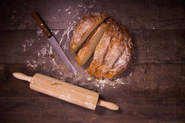 Fresh baked bread covered with flour on a wooden table - 写真・画像