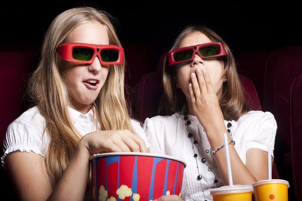 Two beautiful girls watching a movie at the cinema - Foto, afbeelding