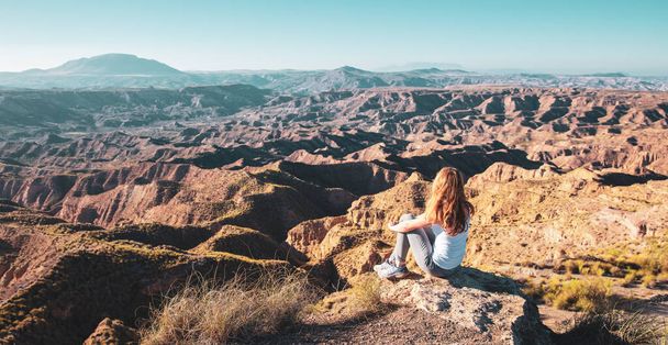 Happy woman sitting on rock enjoying panoramic view of Gorafe desert in Spain- travel destination,  freedom,  adventure concept - Foto, imagen