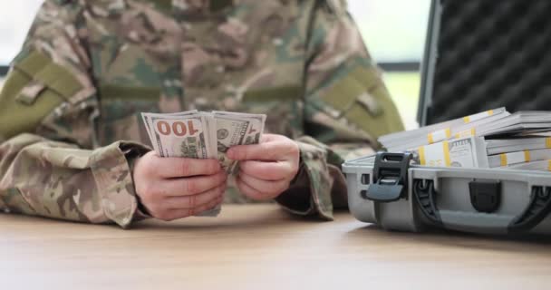 Ein Militärmann, der am Tisch sitzt, zählt Dollars, eine Großaufnahme. Finanzielle Unterstützung für Krieg, Zeitlupe - Filmmaterial, Video