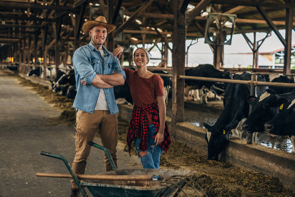 Female and male farmer standing in a stall and proudly looking at the camera. - Fotoğraf, Görsel
