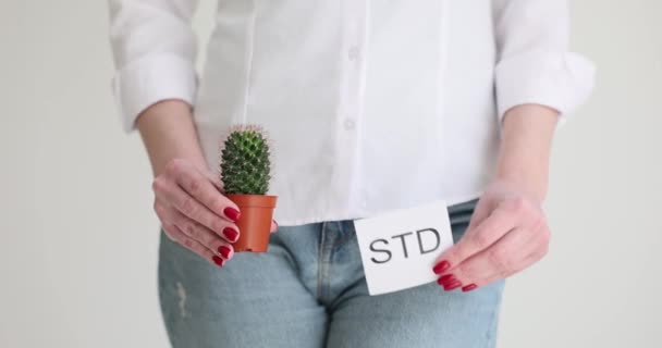 Das Mädchen hält einen Kaktus und ein Blatt Papier, es wird von STD geschrieben. Die Folgen sexuell übertragbarer Krankheiten - Filmmaterial, Video