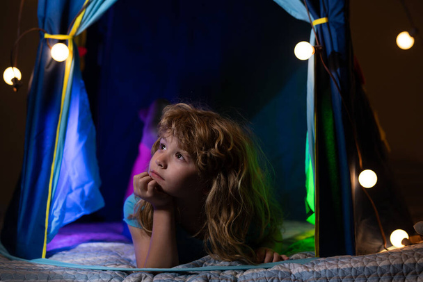 Night kids bedtime. Child lying in kids tent. Little before going to bed. Night dream. Kid dreams in tent at home. Childhood dream. Daydreamer child. Dreams and imagination. Dreamy kids - Photo, image