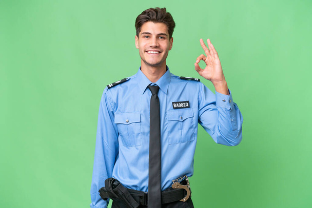 Young police man over isolated background showing ok sign with fingers - Photo, Image