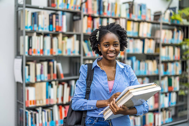 Portrait of black female student standing in a library - Photo, image