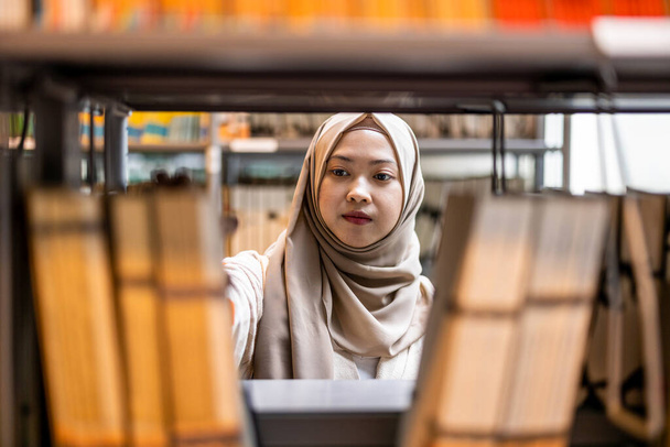 Portrait of asian muslim female student standing in a library - Foto, Imagem