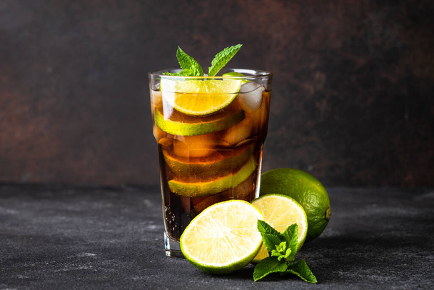 Cuba Libre alcoholische cocktail, ijsdrank op donkere achtergrond. - Foto, afbeelding