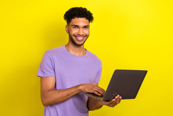 Photo of young man hold netbook online corporate meeting wear purple t-shirt use laptop order clothes isolated on yellow color background. - Fotografie, Obrázek
