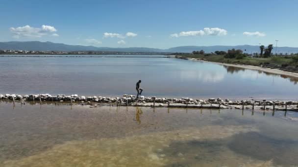 Μελαχρινός άντρας περπατά σε μια λωρίδα γης που χωρίζει δύο λίμνες - Πλάνα, βίντεο