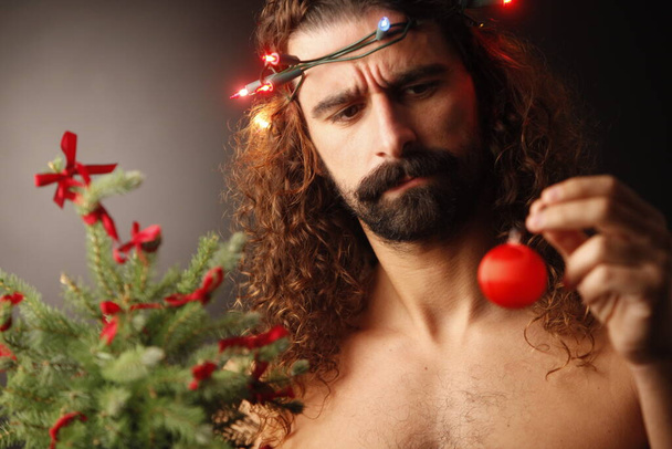 young handsome bearded man with christmas tree on blurred background  - Photo, Image