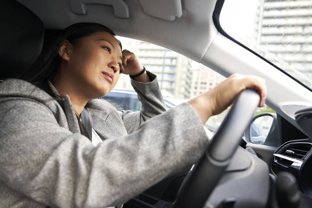 Pensiva donna cinese alla guida di una macchina  - Foto, immagini