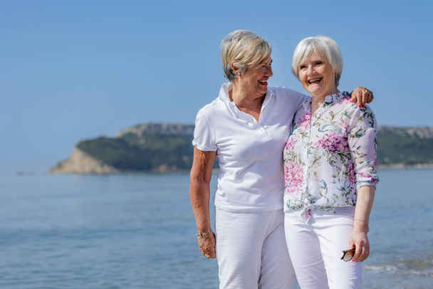 felices mujeres mayores sonriendo juntas en una playa - Foto, Imagen