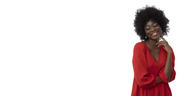 Mujer joven positiva con peinado afro y piel oscura en vestido rojo sobre fondo blanco aislado. - Foto, Imagen