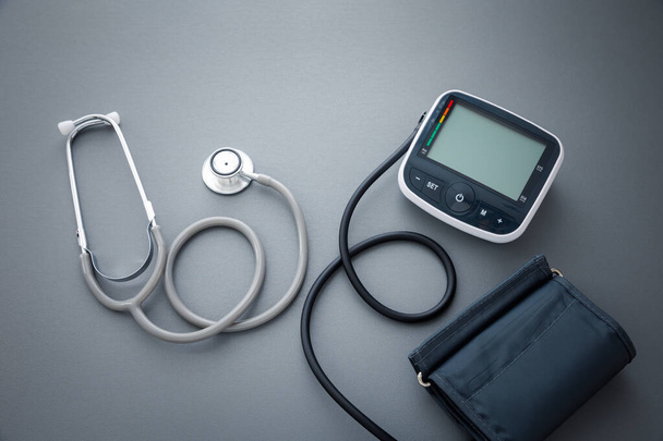 estetoscopio con máquina de medición de presión arterial sobre fondo gris oscuro, concepto de salud - Foto, imagen