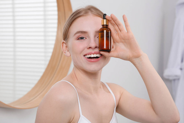 Young woman with bottle of essential oil in bathroom - Photo, Image