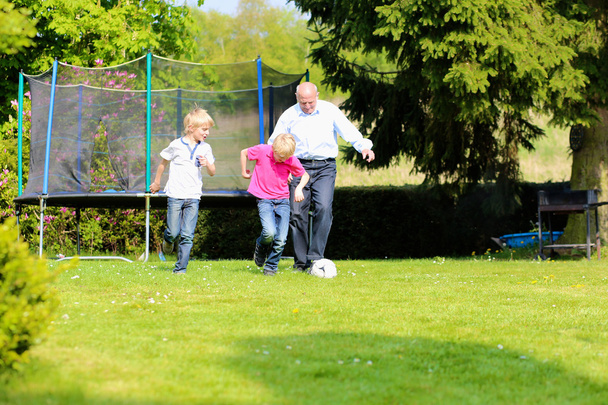 Grandfather with grandsons playing soccer in the garden - Foto, Imagem