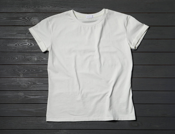Stylish white T-shirt on gray wooden table, top view - 写真・画像