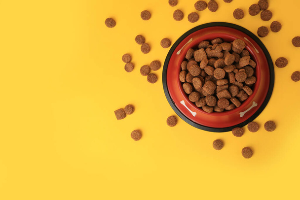 Dry dog food and feeding bowl on orange background, flat lay. Space for text - Fotó, kép