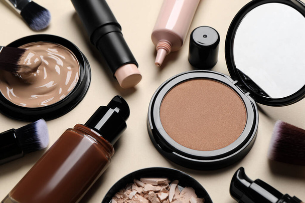 Liquid foundations, beauty accessories and face powders on beige background, closeup - 写真・画像