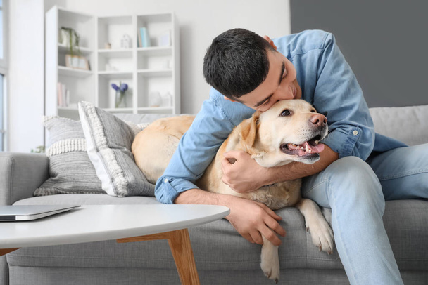 Jovem com cão Labrador bonito sentado no sofá em casa - Foto, Imagem