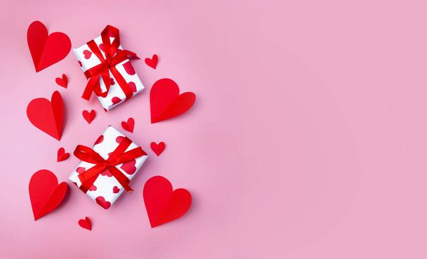 Gift boxes with red hearts on a pink background. The concept of gifts for Valentine's day. Shopping, sale and discounts. Copy space. Flat lay. - 写真・画像