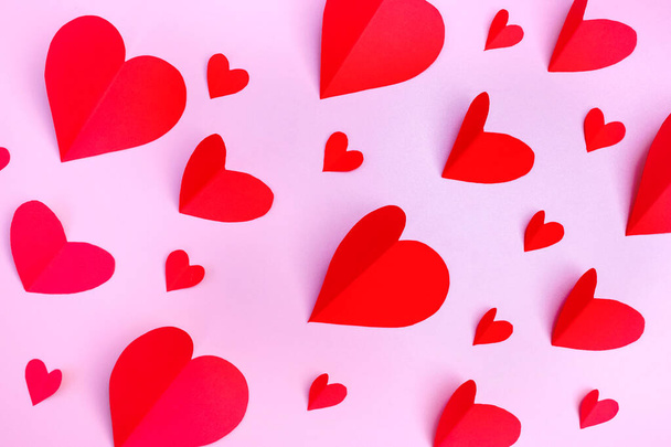 El patrón del papel los corazones rojos sobre el fondo rosado. Concepto del Día de San Valentín. Puesta plana. - Foto, imagen