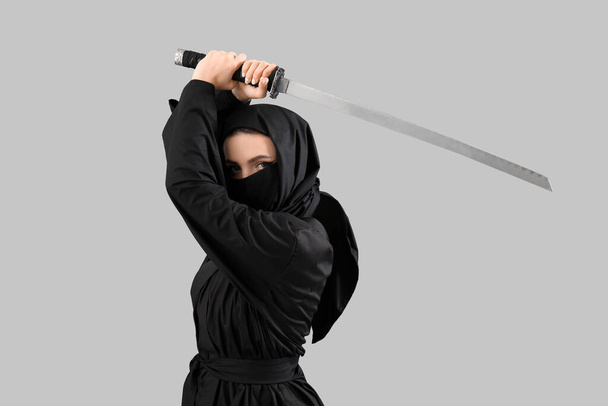灰色の背景に剣を持つ女性忍者 - 写真・画像