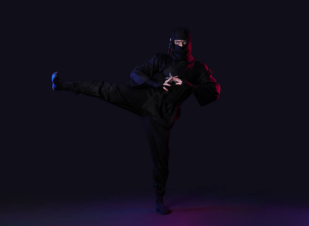 Ninja maschio con shuriken su sfondo nero - Foto, immagini