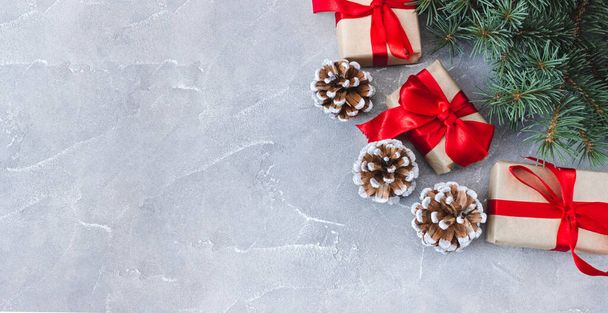 Festive gift boxes with fir branches and cones on a concrete background. New Year and Christmas concept. Flatlay. Copyspace. Postcard. - Φωτογραφία, εικόνα