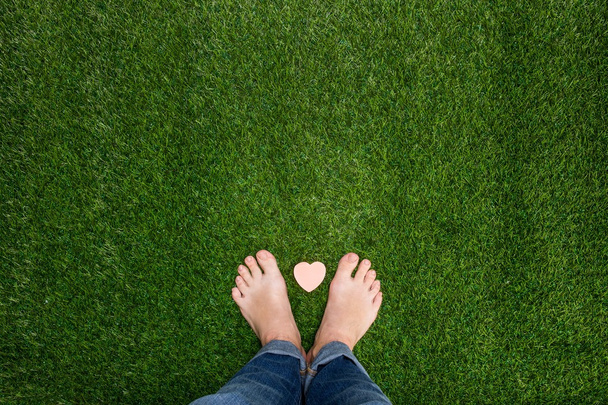 Feet standing on grass with small heart - Fotoğraf, Görsel