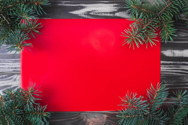 New Year and Christmas red card on a wooden background with fir branches. Flat lay. Copy space. Mock up. - Foto, Imagen