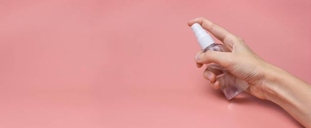 A woman's hand with an antiseptic on a pink background close-up. The concept of hygiene and cleanliness. Disinfectant. Banner. - Foto, imagen