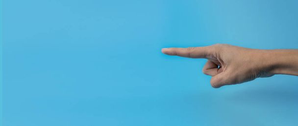 A woman's hand with an index finger on a blue background. Copy space. Banner. - Foto, Imagen