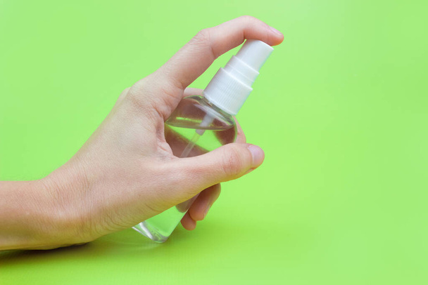 A woman's hand with an antiseptic on a green background close-up. The concept of hygiene and cleanliness. Disinfectant. - Photo, Image