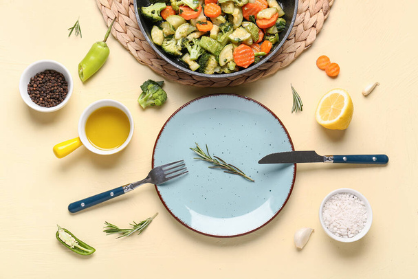 Teller und Pfanne mit leckerem Gemüse auf gelbem Hintergrund - Foto, Bild