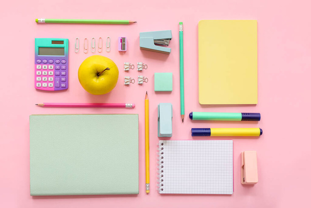 Свіже яблуко з калькулятором і різні канцелярські товари на рожевому фоні
 - Фото, зображення