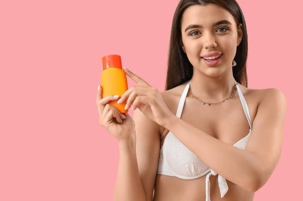 Young woman with sunscreen cream on pink background - Foto, imagen