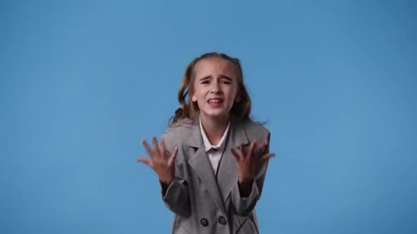 4k Video von einem Mädchen, das für ein Video auf blauem Hintergrund posiert. Konzept der Emotionen. - Filmmaterial, Video