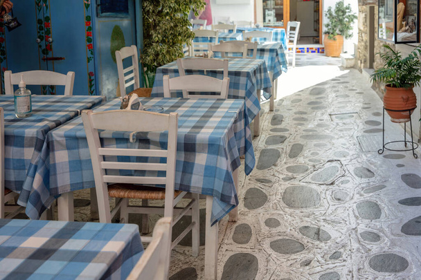 屋外伝統的な居酒屋レストランの宛先ギリシャ,ティノス島ホラ町キクラデス.空の椅子テーブル、舗装された路地、夏の晴れた日. - 写真・画像