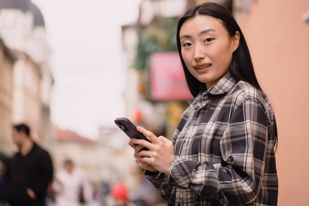 Porträt einer schönen Koreanerin in der Altstadt. Asiatin in lässiger Kleidung telefoniert mit moderner Technologie und Lifestyle. - Foto, Bild