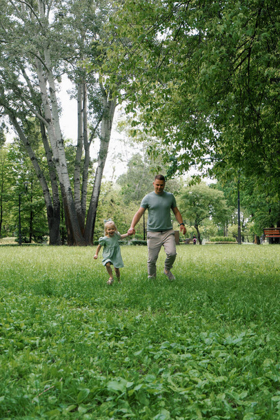 Heureux père et petite fille courir ensemble dans le parc se tenant la main Jeu de famille fête des pères - Photo, image