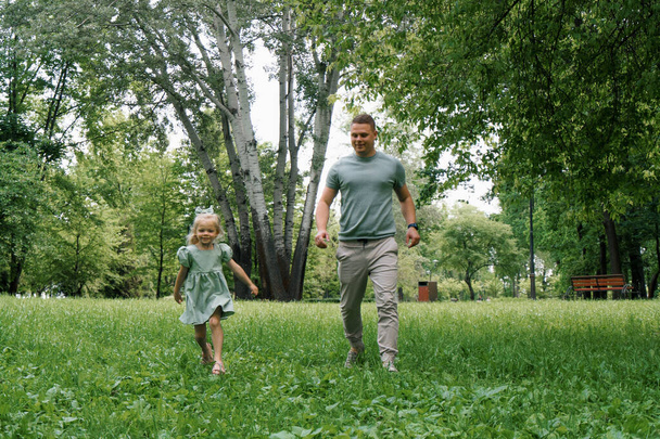 Iloinen isä ja pieni tytär juoksevat yhdessä puistossa Perheleikki Isänpäivä Lapsuus - Valokuva, kuva