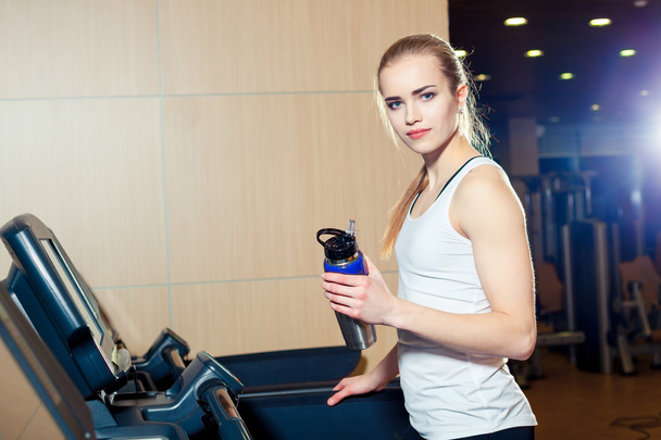 Pretty girl working out in a treadmill at the gym and smiling - Foto, imagen
