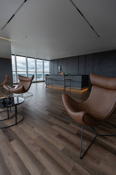 dark minimalistic design of a trendy chic studio apartment with panoramic windows on a high floor overlooking the city - Zdjęcie, obraz