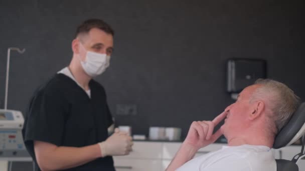 Egy idősebb férfi arcának megjelölése plasztikai műtét előtt. A sebész azzal kezdi, hogy előkészíti a bőrt a műtétre - Felvétel, videó