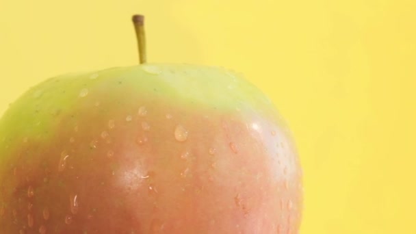 Una mela matura e succosa ruota durante le riprese. Sparatoria di obiettivo di pubblicità di una mela su uno sfondo giallo. Video verticale - Filmati, video