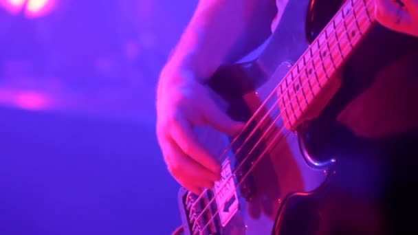 Close-up van muzikant die basgitaar speelt tijdens rockconcert. Wereldtournee van populaire muzikanten. - Video