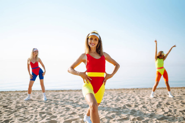 Happy woman in colorful swimsuits are dancing in the morning at the beach. oncept of sports, fitness, aerobics. Active sport. - Fotó, kép